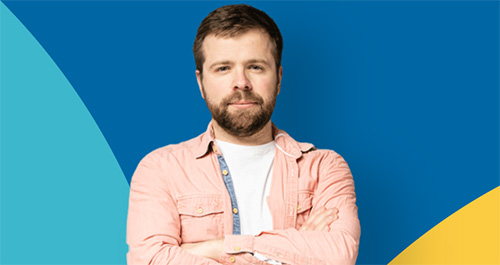 ein Mann mit gekreuzten Armen, der vor einem blauen und gelben Hintergrund steht