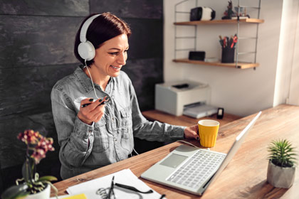 eine Frau sitzt an einem Schreibtisch mit Kopfhörern auf